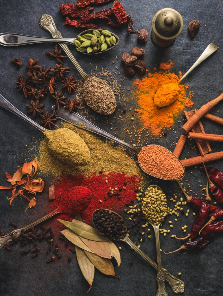 pexels-photo-2802527-2802527 Vibrant array of spices including turmeric, cumin, and chili arranged on a dark surface.